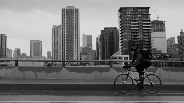 Video Reference: White, Bicycle, Urban area, Black, Metropolitan area, City, Daytime, Black-and-white, Human settlement, Mode of transport, Person