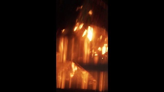 Video Reference: Heat, Flame, Fire, Lighting, Darkness, Light, Stop, Lit, Dark, Traffic, Sitting, Building, Street, Sign, Red, Pole, Standing, Blurry, Signal, Night, Man, City, Fireplace, Fireworks