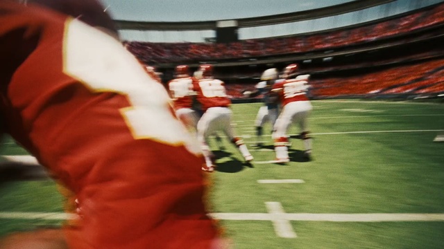 Video Reference: Sports, Ball game, Sport venue, Player, Team sport, Football player, Stadium, Tournament, Sports equipment, Arena football, Person, Playing, Grass, Game, Young, Ball, Man, Soccer, Holding, Girl, Field, Group, Woman, People, Standing, Water, Red, White, Court, Football helmet, Football, Clothing, Helmet, American football, Gridiron football, Canadian football, Sprint football