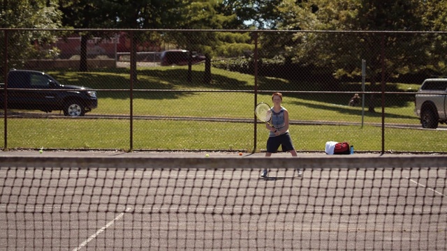 Video Reference: Tennis court, Sport venue, Net, Grass, Line, Fence, Tree, Tennis, Car, Chain-link fencing