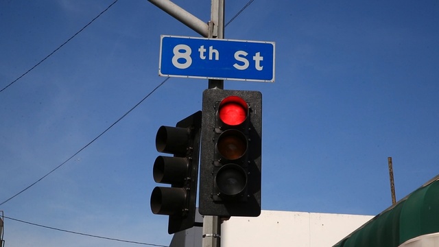 Video Reference: traffic light, signaling device, sky, light fixture, signage, public utility, street sign, sign, traffic sign, Person