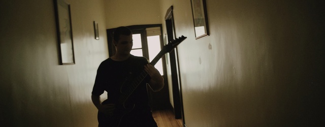 Video Reference: Plaster, Person, Indoor, Standing, Man, Black, Front, Room, Mirror, Woman, Young, Dark, Laptop, Computer, Holding, Suitcase, Luggage, White, Refrigerator, Kitchen, Bed, Clock, Wall, Clothing, Musical instrument, Human face, Guitar
