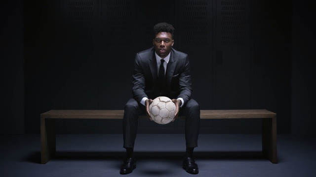 Video Reference: sitting, man, gentleman, suit, darkness, lighting, human, furniture, table, formal wear, Person