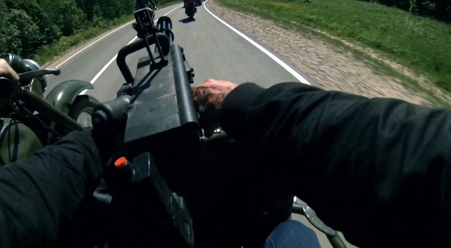 Video Reference: Motor vehicle, Vehicle, Mode of transport, Automotive tire, Asphalt, Automotive wheel system, Driving, Automotive exterior, Photography, Auto part, Outdoor, Motorcycle, Grass, Road, Person, Man, Street, Side, Parked, Car, Riding, Sitting, Bicycle, Black, Traffic, Helmet, Red, Mirror, Standing, Sign, People, Weapon, Land vehicle, Scooter