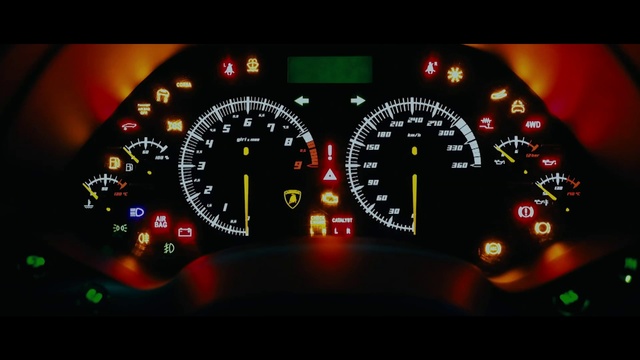 Video Reference: Speedometer, Gauge, Auto part, Measuring instrument, Tachometer, Tool, Odometer, Car, Vehicle, Trip computer, Thing, Indoor, Clock, Monitor, Black, Computer, Sitting, Table, Screen, Desk, Light, Side, Hanging, Green, Red, Keyboard, Standing, White, Room, Man, Fuel gauge, Text, Time