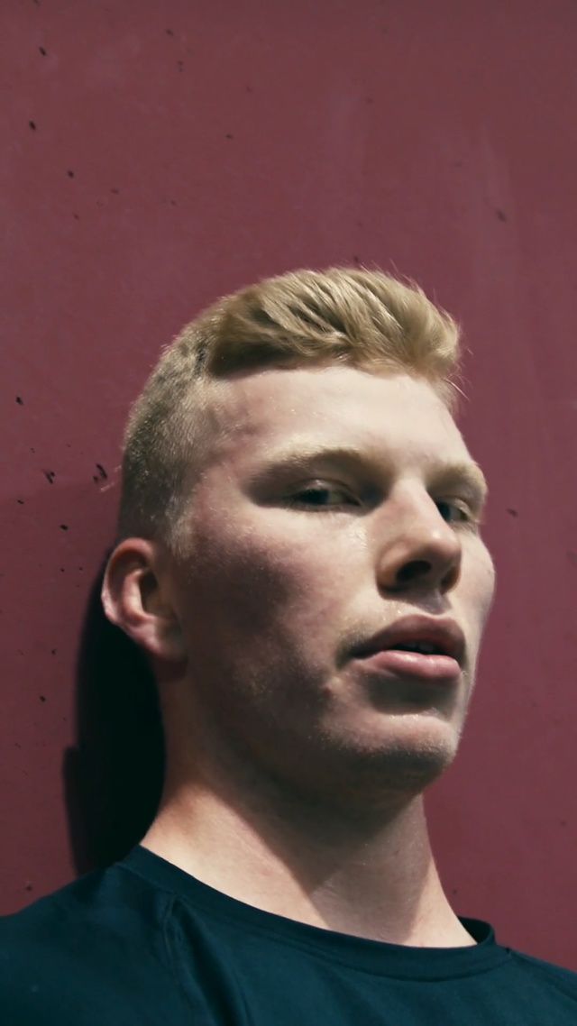 Video Reference: Face, Hair, Chin, Forehead, Head, Hairstyle, Nose, Cheek, Eyebrow, Neck, Person, Man, Indoor, Building, Looking, Standing, Holding, Wearing, Front, Camera, Shirt, Posing, Young, Black, Glasses, Red, Suit, White, Umbrella, Wall, Human face, Portrait, Clothing