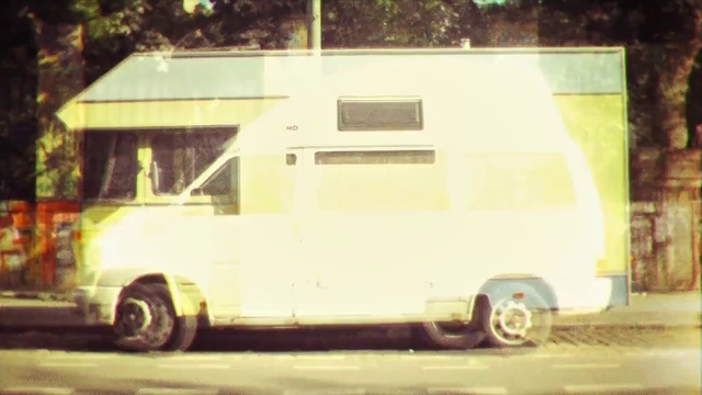 Video Reference: Land vehicle, Motor vehicle, Vehicle, Car, Rv, Transport, Mode of transport, Commercial vehicle, Van, Food truck, Road, Outdoor, Street, Building, Truck, Bus, Front, Driving, Parked, White, Sitting, Man, Riding, City, Side, Yellow, Large, Motorcycle, Fire, Standing, Tree, Wheel, Text, Auto part, Curb