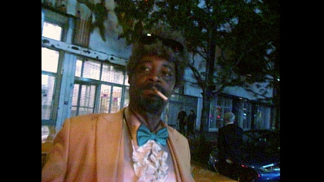 Video Reference: Photograph, People, Snapshot, Human, Forehead, Adaptation, Cool, Gentleman, Fun, Temple, Person, Man, Indoor, Window, Front, Table, Sitting, Wearing, Looking, Holding, Standing, Posing, Young, Laptop, Food, Glasses, Shirt, Suit, Computer, Large, Glass, White, Room, Hat, Cat, Human face, Clothing