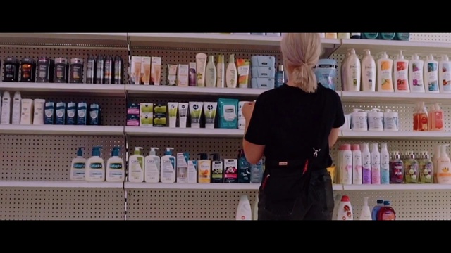 Video Reference: Product, Alcohol, Shelf, Shelving, Furniture, Retail, Building, Person, Indoor, Bottle, Refrigerator, Open, Front, Food, Man, Counter, Table, Standing, Holding, White, Large, Young, Kitchen, Text, Soft drink, Drink, Clothing