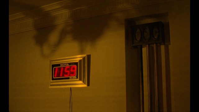 Video Reference: Red, Light, Wall, Lighting, Room, Wood, House, Window, Visual arts, Art, Object, Thing, Clock, Sign, Dark, Mounted, Sitting, Street, Front, Side, Night, Large, White, Lit, Orange, Hanging, Standing, Screen, Television, Man, City, Yellow, Text