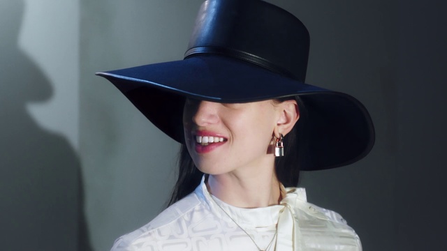 Video Reference: Hair, Hat, Clothing, Fashion accessory, Beauty, Lip, Fedora, Sun hat, Fashion, Headgear, Person, Wearing, Headdress, Indoor, Young, Shirt, Boy, Holding, Black, Man, White, Computer, Little, Head, Laptop, Baseball, Table, Standing, Woman, Blue, Teeth, Wall, Cowboy hat, Human face, Costume hat, Smile, Sombrero, Cap