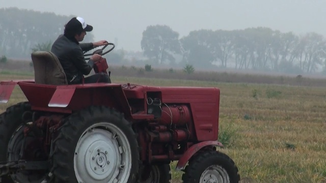 Video Reference: agricultural machinery, vehicle, tractor, field, agriculture, grass, farm, automotive tire, all terrain vehicle, harvester, Person