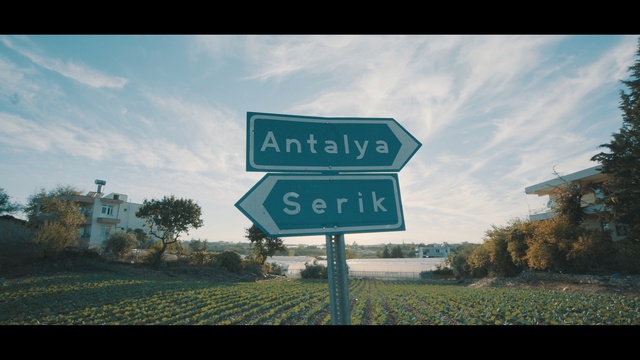 Video Reference: Sky, Street sign, Signage, Natural landscape, Text, Road, Sign, Cloud, Font, Tree