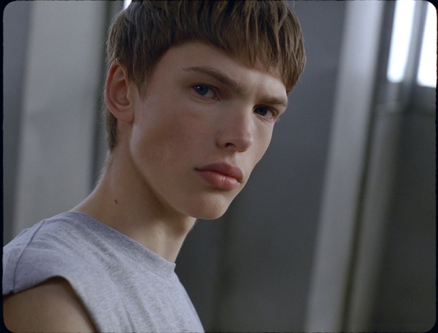 Video Reference: Hair, Face, Hairstyle, Chin, Forehead, Eyebrow, Head, Nose, Jaw, Cheek, Person, Indoor, Young, Woman, Front, Looking, Window, Holding, Shirt, Standing, Boy, Laptop, Camera, Hand, Girl, Computer, Using, Little, Wearing, Table, Smiling, Mirror, Man, White, Room, Pizza, Red, Video, Remote, Human face, Wall, Clothing, Portrait, Neck, Crop, Lip