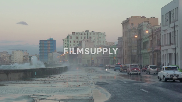 Video Reference: Atmospheric phenomenon, Urban area, City, Downtown, Metropolitan area, Haze, Human settlement, Morning, Neighbourhood, Town, Outdoor, Road, Building, Street, Car, Light, Water, Driving, Traffic, Large, Intersection, Riding, Tall, Man, Hydrant, Red, White, Rain, Standing, Sky, Fog, Vehicle, Skyscraper, Way, Day, Highway