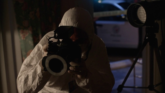 Video Reference: Photography, Personal protective equipment, Darkness, Space, Night, Camera operator, Person, Indoor, Man, Sitting, Small, Holding, Front, Young, White, Bed, Room, Wearing, Table, Standing, Air