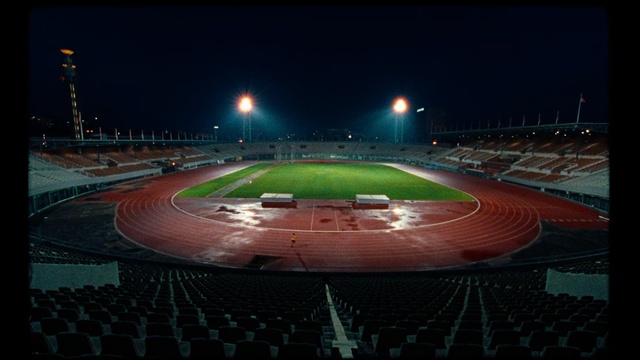 Video Reference: Sport venue, Stadium, Arena, Night, Atmosphere, Race track, Sky, Soccer-specific stadium, Sports, Competition event, Outdoor, Sitting, Plane, Light, Large, Runway, Red, Table, Green, Lit, Engine, Airplane, Track, White, Water, Tarmac, Parked, Blue, Street, Baseball