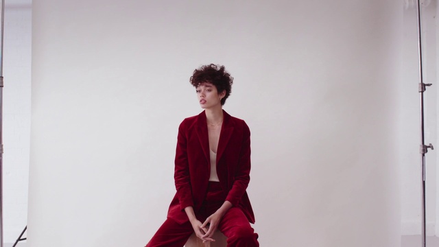 Video Reference: Red, Clothing, Maroon, Shoulder, Fashion model, Standing, Fashion, Dress, Sitting, Neck, Person