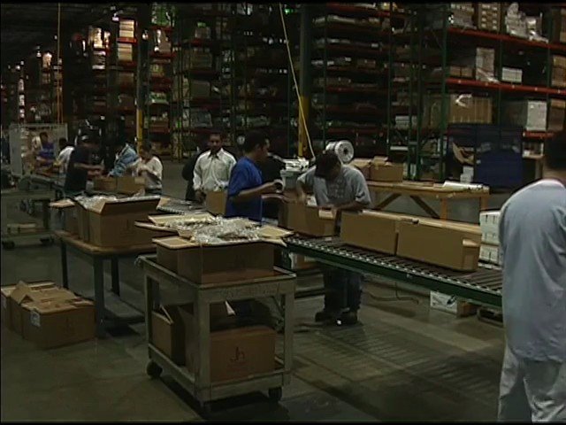 Video Reference: warehouse, factory, assembly line, packing, boxes, workers, industrial, logistics, distribution, storage, shipping, production, indoor, conveyor, manual labor