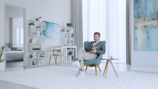 Video Reference: Photograph, Furniture, Sitting, Room, Interior design, Design, Chair, Desk, Material property, White-collar worker, Person