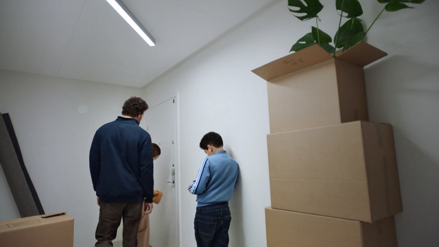 Video Reference: Wall, Room, Architecture, Ceiling, Person, Indoor, Man, Standing, Looking, Front, Kitchen, Preparing, Holding, Young, Living, Large, People, Refrigerator, Suitcase, Board, Luggage, Playing, Group, Clothing, Design