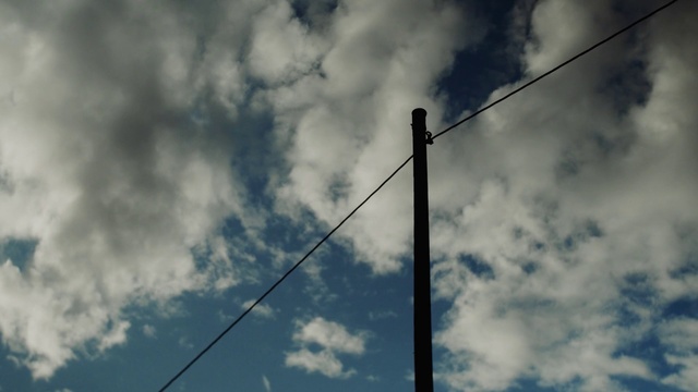 Video Reference: Sky, Cloud, Blue, Daytime, Wire, Atmosphere, Line, Cumulus, Tree, Technology, Person, Outdoor, Cloudy, Clouds, Background, Train, Sitting, High, Smoke, Green, Light, Dark, Track, Hanging, Sign, Old, Pole, Traffic, Red, Air, Airplane, Plane, White, Street, Day, Power line