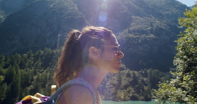 Video Reference: Hair, Nature, Sunlight, Light, Beauty, Wilderness, Hairstyle, Summer, Tree, Fun, Person, Outdoor, Mountain, Man, Holding, Standing, Front, Wearing, Woman, Hand, Carrying, Young, Red, Flying, Riding, People, White, Motorcycle, Human face, Glasses, Sunglasses, Goggles, Crowd