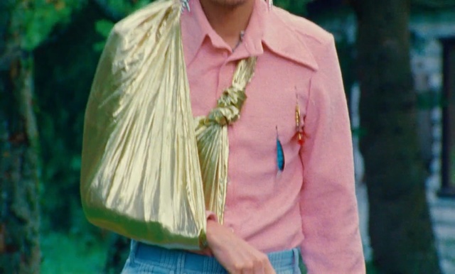 Video Reference: Green, Clothing, Pink, Yellow, Shirt, Turquoise, Peach, Outerwear, Fashion, Sleeve, Person, Outdoor, Wearing, Man, Holding, Standing, Front, Smiling, Carrying, Young, Walking, Woman, Dress, Hat, Blue, Red, White, Street, Tree, Human face, Fashion accessory, Smile