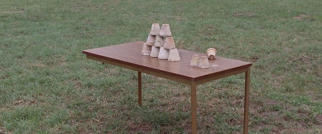 Video Reference: Furniture, Table, Coffee table, Outdoor table, Wood, Outdoor furniture, Plywood, Hardwood, Picnic table, Desk, Grass, Outdoor, Field, Wooden, Sitting, Standing, Small, Grassy, Set, Chair, Green, Brown, Old, Large, Man, Fire, Laying, People, Bench, Dining table