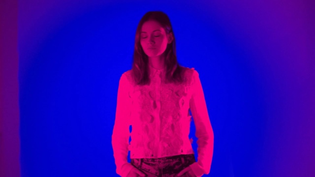 Video Reference: Blue, Violet, Purple, Electric blue, Cobalt blue, Magenta, Red, Light, Pink, Performance, Person, Stage, Holding, Standing, Front, Woman, Wearing, Room, Young, Shirt, Man, Board, Human face, Clothing