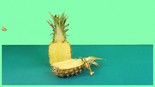 Video Reference: Pineapple, Ananas, Plant, Fruit, Bromeliaceae, Cake, Table, Sitting, Small, Front, Green, Food, Holding, Man, Plate, Display, Blue, Yellow, Text