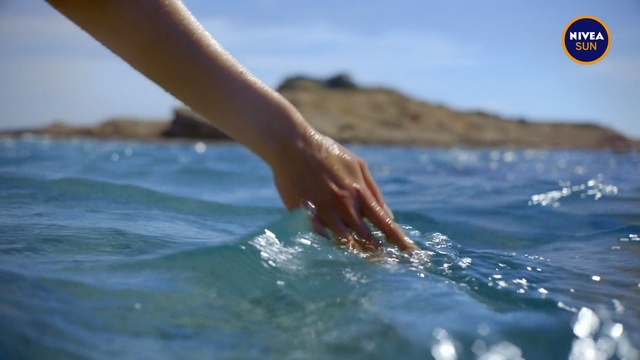 Video Reference: Water, Wave, Sea, Ocean, Surfing equipment, Arm, Recreation, Wind wave, Vacation, Hand, Outdoor, Person, Surfing, Sport, Board, Riding, Young, Man, Laying, Small, Black, Holding, Beach, Blue, Standing, White, Game, Sky, Swimming, Water sport, Swimwear