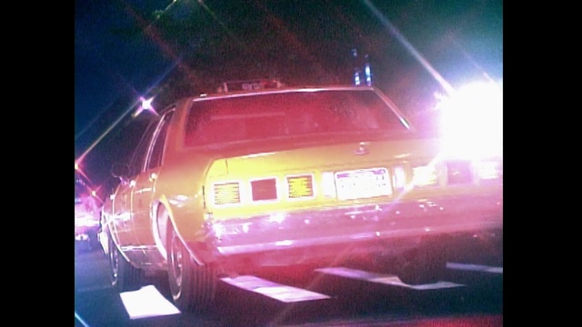 Video Reference: Automotive lighting, Vehicle, Car, Light, Automotive exterior, Mode of transport, Lighting, Automotive tail & brake light, Bumper, Vehicle door, Red, Monitor, Sitting, Night, Lit, Street, Dark, Truck, Table, Bus, Traffic, Stop, City, Parked, Train, Sign, Man, White, Land vehicle, Auto part, Wheel, Text, Vehicle registration plate