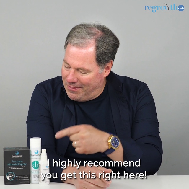 Video Reference: Water, Alcohol, Photo caption, Person, Man, Indoor, Sitting, Holding, Table, Cellphone, Phone, Looking, Front, Computer, Using, Laptop, Hand, Sign, Black, Woman, Remote, Video, Text, Watch, Human face, Clothing