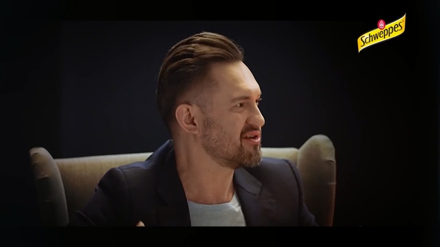 Video Reference: Hair, Face, Facial expression, Cheek, Chin, Forehead, Nose, Head, Facial hair, Ear, Person, Man, Indoor, Looking, Laptop, Front, Sitting, Holding, Screen, Suit, Computer, Using, Table, Standing, Wearing, Room, Television, Food, Shirt, Phone, Remote, White, Screenshot, Human face, Text, Clothing