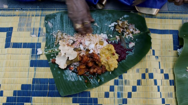 Video Reference: Dish, Food, Cuisine, Leaf, Ingredient, Vegetarian food, Recipe, Produce, Banana leaf rice, Person, Indoor, Table, Sitting, Plate, Black, Dog, Laying, Green, Holding, Man, Hot, Bed, White, Blue, Pizza, Vegetable