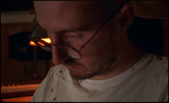 Video Reference: Face, Hair, Eyewear, Nose, Glasses, Chin, Head, Cheek, Lip, Neck, Person, Man, Indoor, Looking, Shirt, Holding, Food, Eating, Mouth, Front, Wearing, Sitting, Close, Young, Smiling, Bite, Pizza, Sandwich, Teeth, Large, Brushing, Standing, Hat, White, Phone, Plate, Kitchen, Hotdog, Human face, Human beard, Selfie, Clothing