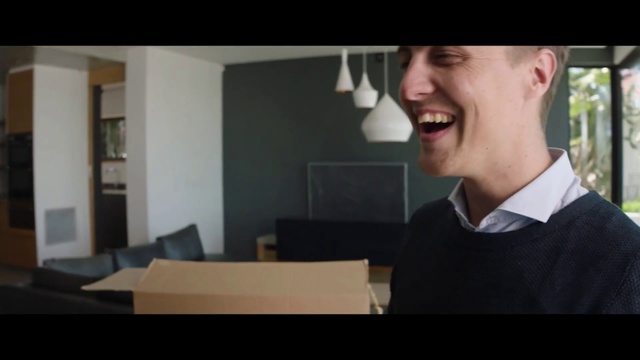 Video Reference: Photograph, Facial expression, Eyewear, Suit, Snapshot, Conversation, Male, Chin, Gentleman, White-collar worker, Person, Man, Indoor, Standing, Table, Front, Holding, Looking, Wearing, Smiling, Screen, Television, Black, Room, Computer, Young, Laptop, Desk, Red, White, Human face, Smile, Text, Clothing, Screenshot