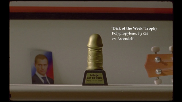 Video Reference: President, Photo, Statue, Guitar  , Person, Indoor, Sitting, Table, Small, Mirror, White, Holding, Light, Food, Man, Woman, Sink, Vase, Room, Text, Bottle