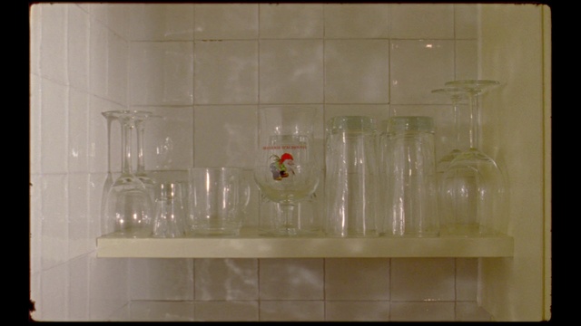 Video Reference: Transparent material, Glass, Tile, Water, Room, Drinkware, Flooring, Plastic, Indoor, Small, Sitting, Table, White, Filled, Empty, Black, Man, Clear, Holding, Standing, Kitchen, Refrigerator, Wall, Sink, Plumbing fixture, Vase, Tap, Shower, Bathtub, Bathroom