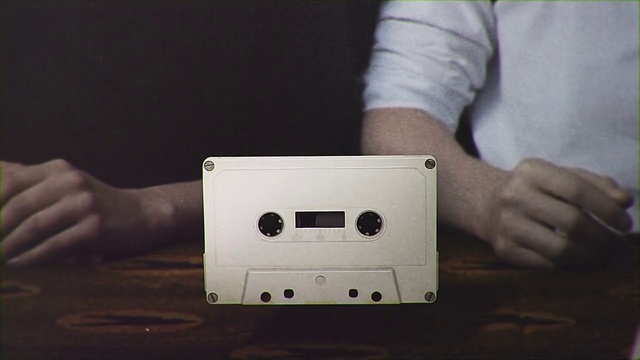 Video Reference: White, Compact cassette, Electronics, Gadget, Electronic device, Technology, Finger, Hand, Material property, Musical instrument accessory, Person, Indoor, Table, Man, Sitting, Front, Using, Laptop, Food, Holding, Computer, Woman, Young, Shirt, Pizza, Plate, Standing, Kitchen, Mobile phone, Ipod, Mac