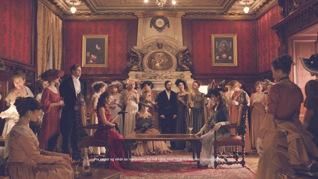 Video Reference: Event, Room, Furniture, Audience, Person, Indoor, People, Table, Group, Woman, Sitting, Man, Old, Living, Standing, Kitchen, Wine, Large, Holding, Train, Clothing, Painting, Picture frame