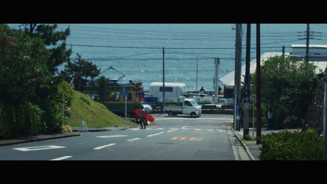 Video Reference: Road, Lane, Mode of transport, Residential area, Street, Transport, Sky, Town, Asphalt, Urban area, Outdoor, Water, View, City, Traveling, Driving, Large, Red, Light, Traffic, White, Riding, People, Sign, Man, Tree, Vehicle, Text, Land vehicle, Car, Highway