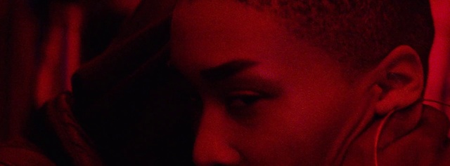 Video Reference: Red, Face, Nose, Black, Lip, Head, Mouth, Eyebrow, Cheek, Close-up, Person, Man, Looking, Dark, Laptop, Room, Wearing, Sitting, Cellphone, Phone, Holding, Talking, Shirt, Hand, Using, Young, Close, Computer, Blurry, Orange, Glasses, Lit, Screen, Cat, Bed, White, Teeth, Brushing, Human face, Eyes