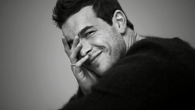 Video Reference: Face, White, Photograph, Black, Facial expression, Black-and-white, Nose, Monochrome photography, Chin, Monochrome, Person, Man, Indoor, Looking, Front, Holding, Glasses, Standing, Camera, Wearing, Hair, Teeth, Dark, Shirt, Brushing, Smiling, Young, Head, Mouth, Room, Brush, Wall, Human face, Black and white, Portrait, Smile, Human beard, Jaw, Forehead, Staring