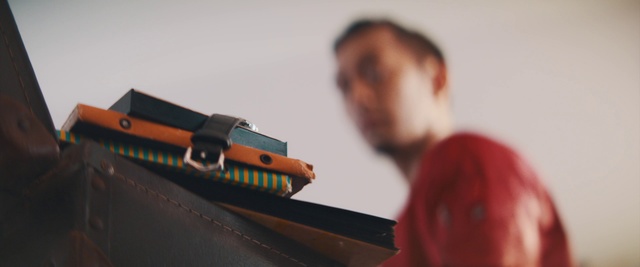 Video Reference: Gun, Indoor, Table, Sitting, Small, Cake, Toy, Man, Red, Holding, Laptop, Girl, Woman, Standing, Television, Mirror, Dog, White, Birthday, Room, Remote, Video, Living, Board, Train