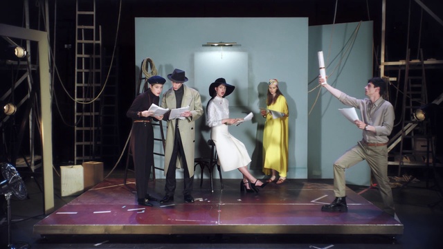 Video Reference: Drama, Heater, Musical, Performance, Performing arts, Musical theatre, Stage, Theatrical property, Event, Acting, Person, Indoor, Man, Standing, Room, Holding, Table, Living, Woman, People, Front, Playing, Couple, Video, Group, Game, Suit, Display, Young, Wii, Floor, Clothing, Dress, Dance, Wedding dress