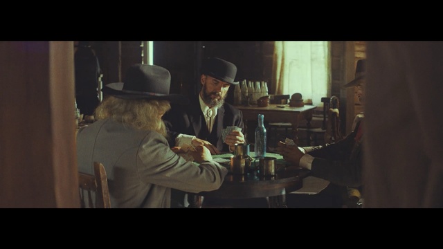 Video Reference: Gentleman, Human, Screenshot, Fun, Movie, Conversation, Photo caption, Alcohol, Scene, Indoor, Person, Man, Table, Photo, Food, Front, Woman, Standing, Glass, Cake, Holding, Wine, White, Plate, Kitchen, Wearing, Fireplace, Restaurant, Large, Young, Sandwich, People, Hat, Fashion accessory, Fedora, Cowboy hat, Sun hat, Clothing, Bottle, Human face, Drink
