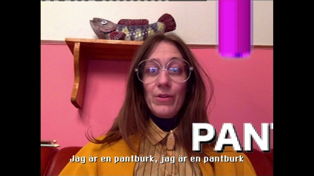 Video Reference: Eyewear, Hair, Face, People, Facial expression, Glasses, Photo caption, Hair coloring, Nose, Head, Person, Indoor, Woman, Table, Photo, Orange, Front, Holding, Computer, Sitting, Monitor, Screen, Laptop, Man, Desk, Standing, Wearing, Keyboard, Sign, Large, Young, Display, White, Shirt, Human face, Text, Smile, Sunglasses, Goggles, Screenshot, Selfie, Clothing, Fashion accessory