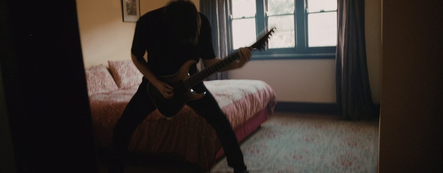 Video Reference: Guitarist, Room, Leg, Musical instrument, Musician, Guitar, Bed, Plucked string instruments, Furniture, Indoor, Person, Window, Woman, Looking, Young, Man, Sitting, Black, Holding, Standing, Playing